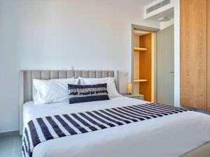 a large white bed with a black and white striped blanket at Sapphire apartment - Paros Gem in Naousa