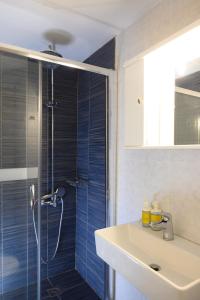 ein Badezimmer mit einem Waschbecken und einer Dusche mit blauen Fliesen in der Unterkunft Havania Apartments in Agios Nikolaos