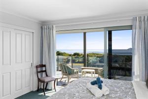 a bedroom with a bed and a balcony with a view at Oceanview on Broadway in Waihi Beach +12 photos