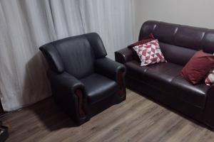 a leather chair and a couch in a living room at Apartamento prático, simples CDHU. in Itatiba