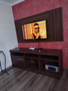 a entertainment center with a television on a red wall at Apartamento prático, simples CDHU. in Itatiba