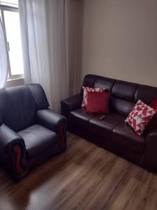 a living room with a leather couch and a chair at Apartamento prático, simples CDHU. in Itatiba