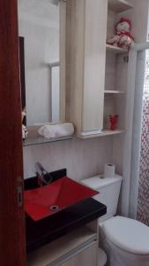 a bathroom with a red sink and a toilet at Apartamento prático, simples CDHU. in Itatiba