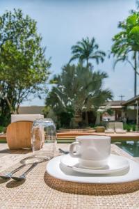 una mesa con una taza de café blanca y una copa en Pousada Pazuu, en Ubatuba