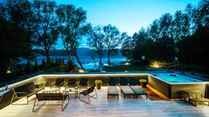 a deck with chairs and a swimming pool at night at Willa Perła Jezior in Mrągowo