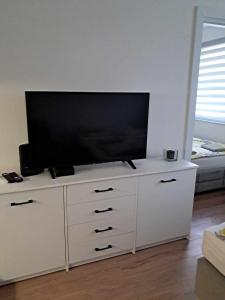 TV de pantalla plana en la parte superior de un armario blanco en Apartament Julia 1-4 os parter Centrum, en Kielce
