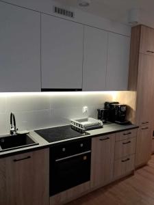 a kitchen with white cabinets and a black stove top oven at Apartament Julia 1-4 os parter Centrum in Kielce