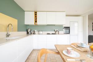 een keuken met witte kasten en een houten tafel bij Large house with garden in Versailles - Welkeys in Versailles