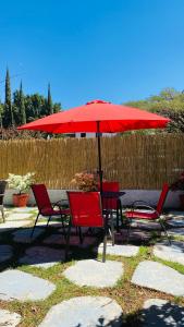 een tafel en stoelen met een rode parasol bij Alojamiento tres pinos in Yelateni