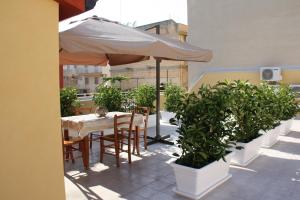 un tavolo con ombrellone su un balcone con piante in vaso di Casa Viola a Pozzallo