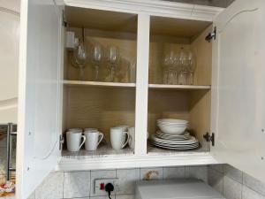 a kitchen cabinet filled with dishes and glasses at Perculiar Homes in Birmingham