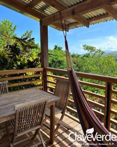 a hammock on a deck with a table and chairs at Clave Verde Ecolodge in Las Terrenas