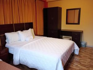 una camera da letto con un grande letto con lenzuola bianche di Madison Suite a Tacna