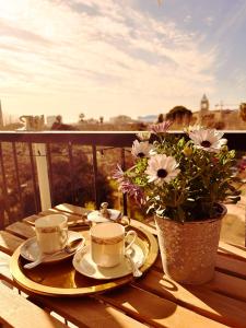 a table with two cups and plates and a vase with flowers at Guest House Camilla in Alghero