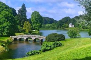 a bridge over a lake in a park at Large historic family home nr Longleat and Bath in Warminster
