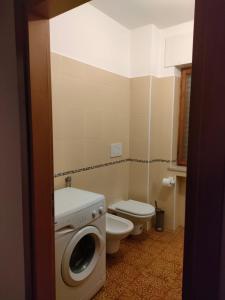 a bathroom with a toilet and a washing machine at Sunflower Apartment in Belluno