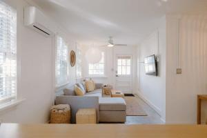 a white living room with a couch and some windows at The Bungalow Lounge by WB Abodes in Wrightsville Beach