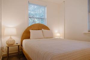 a bedroom with a bed with a wooden headboard and a window at The Bungalow Lounge by WB Abodes in Wrightsville Beach