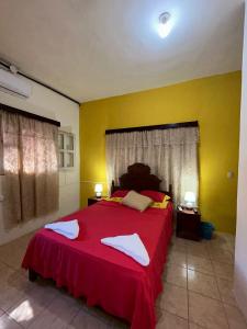 1 dormitorio con 1 cama roja y 2 toallas en Casa Maya Itza en Flores