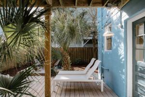 um alpendre com um banco branco numa casa azul em The Bungalow Lounge by WB Abodes em Wrightsville Beach