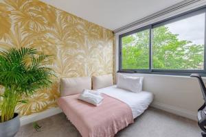 a room with a couch with a plant and a window at Modern & Bright 2 Bed with Pvt Balcony in Islington in London