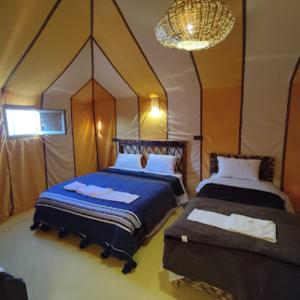 a bedroom with two beds and a chandelier at Blue Sky Luxury Camp in Merzouga