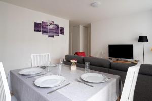 a dining room table with white plates and a couch at Bright T4 with balcony in Saint-Ouen - Welkeys in Saint-Ouen
