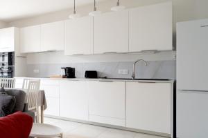 a white kitchen with white cabinets and a sink at Bright T4 with balcony in Saint-Ouen - Welkeys in Saint-Ouen