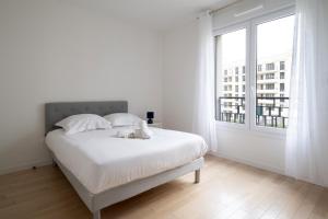a white bedroom with a bed and a large window at Bright T4 with balcony in Saint-Ouen - Welkeys in Saint-Ouen
