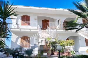 a white building with stairs and palm trees at La perla sulla spiaggia in Alcamo Marina