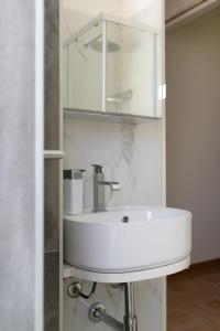 een badkamer met een witte wastafel en een spiegel bij La perla sulla spiaggia in Alcamo Marina