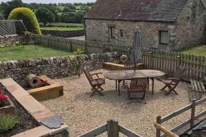 a patio with a table and chairs and an umbrella at The Old Coop Barn in Brassington