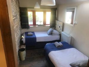 a bedroom with two beds and two windows at The Old Coop Barn in Brassington