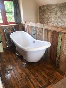 a white bath tub in a bathroom with wooden floors at The Old Coop Barn in Brassington