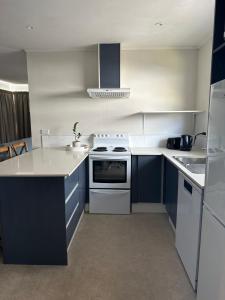 una cocina con electrodomésticos blancos y armarios azules en Hilltop Cottage en Taupo