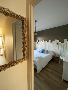 Schlafzimmer mit einem weißen Bett und einem Spiegel in der Unterkunft Les balcons de Bouzigues in Bouzigues