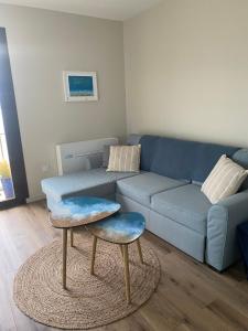 ein Wohnzimmer mit einem blauen Sofa und 2 Hockern in der Unterkunft Les balcons de Bouzigues in Bouzigues