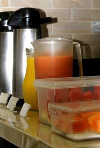 a counter with containers of fruit and a pot of juice at Hotel Hellyus in Brasília