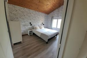 ein Schlafzimmer mit einem weißen Bett und einer Holzdecke in der Unterkunft Les lauriers : piscine chauffée et climatisation in Sigoulès