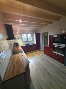 eine große Küche mit Holzböden und roten Schränken in der Unterkunft Les lauriers : piscine chauffée et climatisation in Sigoulès