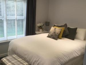 a bedroom with a white bed with pillows and a window at Cherry Bungalow Guesthouse in Shrivenham