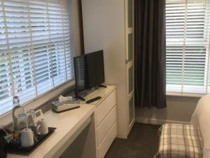 um quarto com uma televisão numa cómoda com uma cama em Cherry Bungalow Guesthouse em Shrivenham