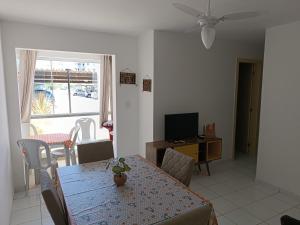 a dining room with a table and a television at Mar de Aruana - Apartamento Suíte com Ar Aracaju-SE in Aracaju