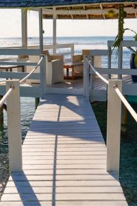 a wooden boardwalk with tables and benches on the beach at Motu Fara Private Island in Avatoru