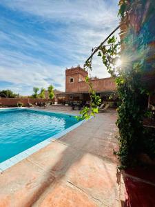 a swimming pool with a building in the background at La Kasbah du Jardin in Aït Benhaddou