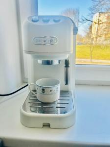 una cafetera con una taza en una encimera en Ezero apartamentai, en Šiauliai