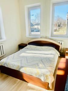 a bed in a bedroom with two windows at Ezero apartamentai in Šiauliai