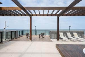 eine Terrasse mit Stühlen und Meerblick in der Unterkunft Aptos completos com vista mar pé na areia em Barra Velha em condomínio Resort com Spa, Piscina, quadra de futebol, Sala de jogos, brinquedoteca, Complexo com diversos comércios in Barra Velha