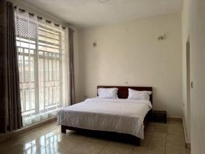 a bedroom with a large bed and a large window at Alma Residence Apartment in Rubavu