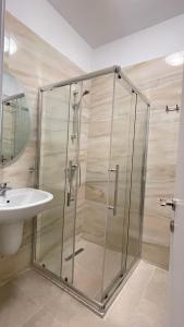 uma cabina de duche em vidro na casa de banho com um lavatório em Simplicity Apartment em Tirana
